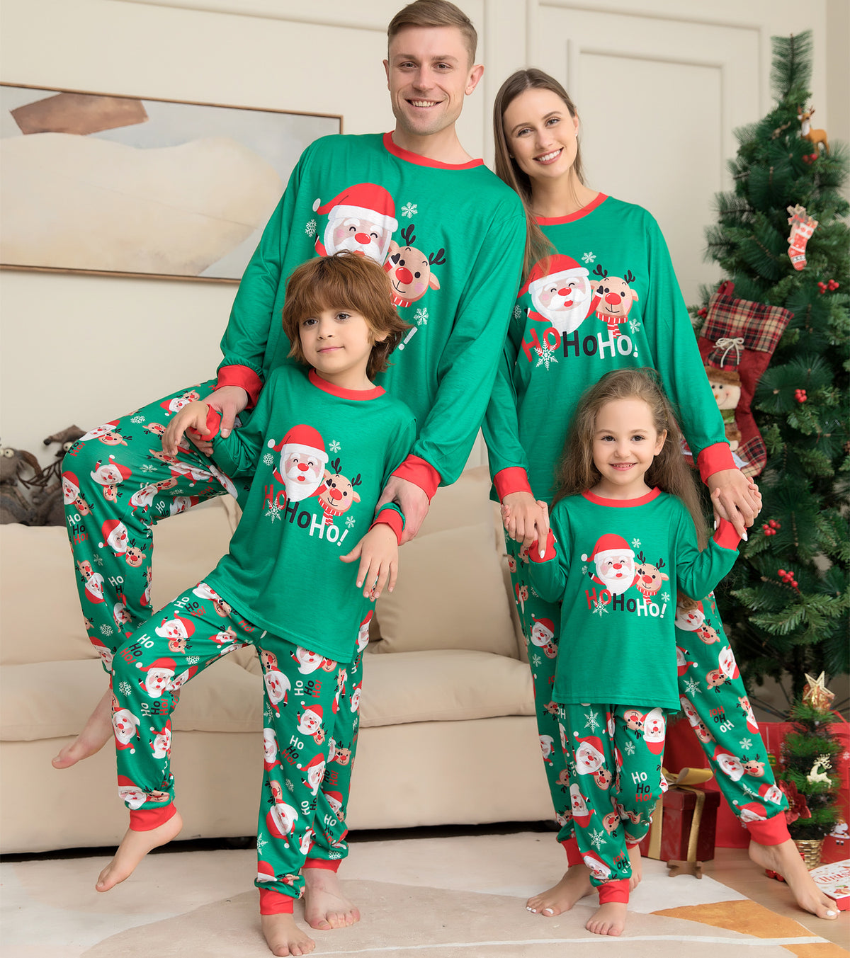Family in matching green Santa Christmas pajamas by the tree